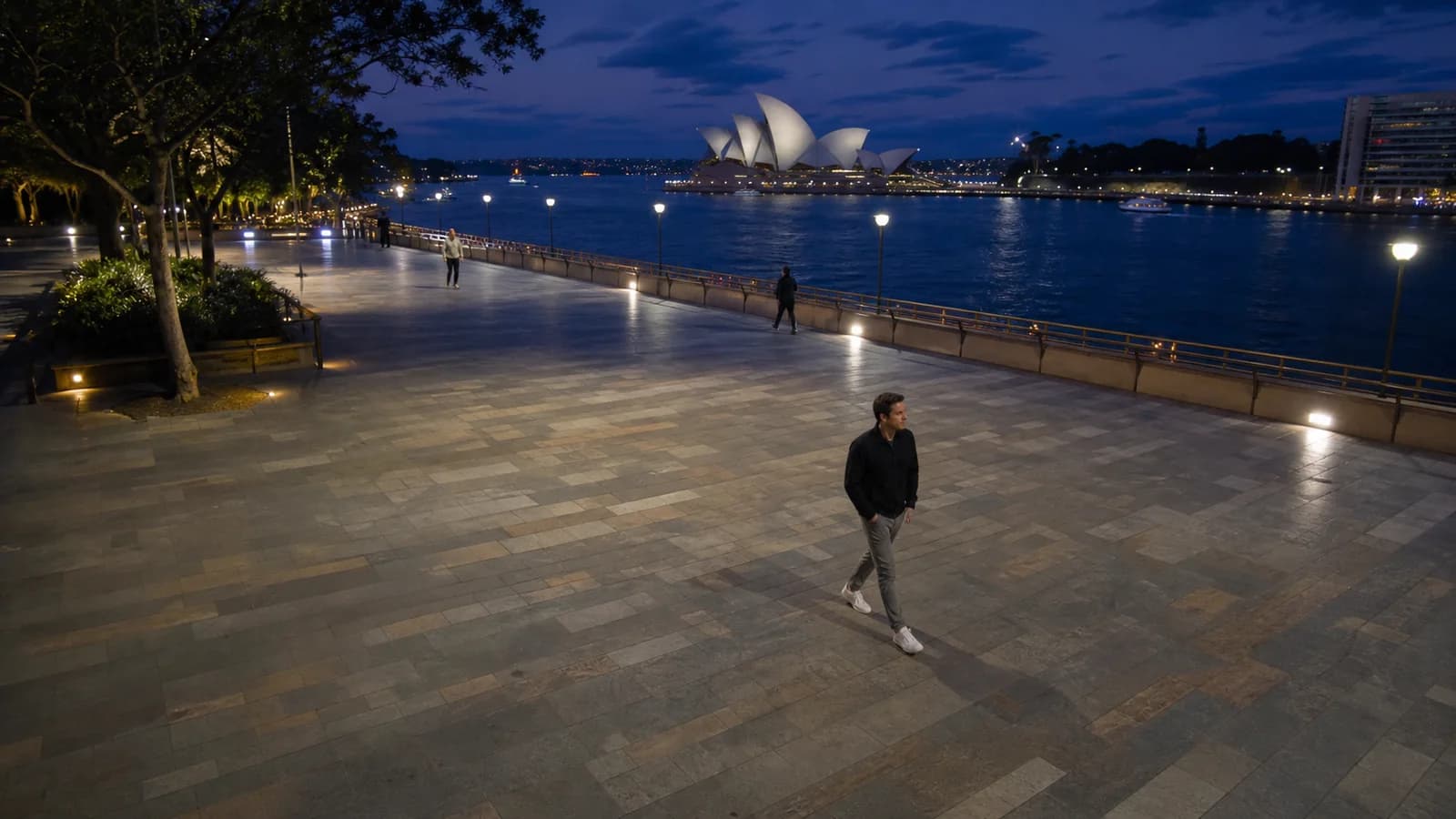 Sydney waterfront promenade with pedestrians and the Opera House in the distance